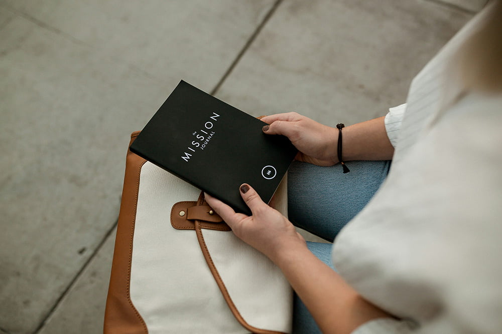 woman holding brochure saying "mission journal"